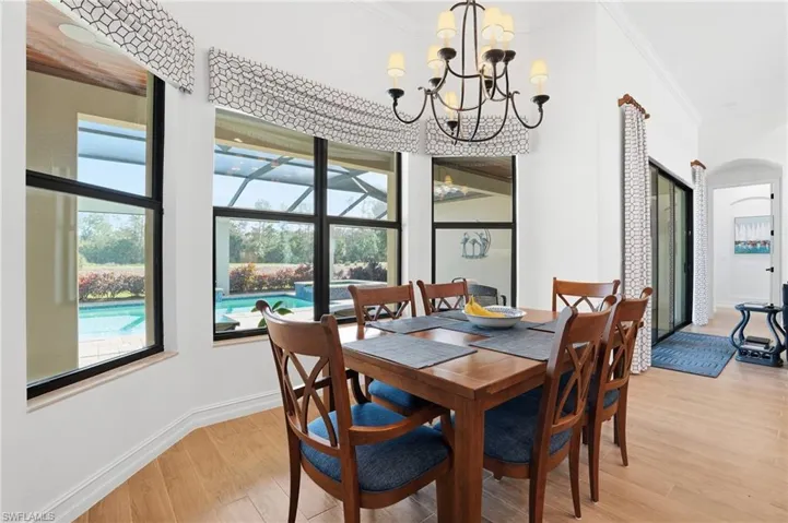 Dining room featuring crown molding, light wood-type flooring, arched walkways, and a chandelier