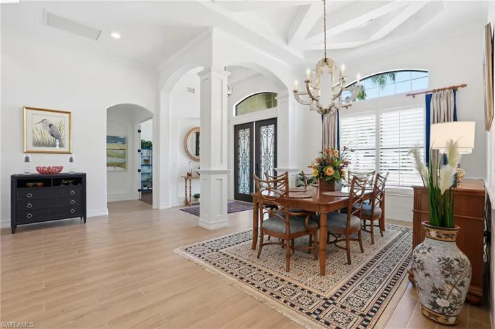 Dining space featuring ornamental molding, arched walkways, beamed ceiling, light wood finished floors, and coffered ceiling