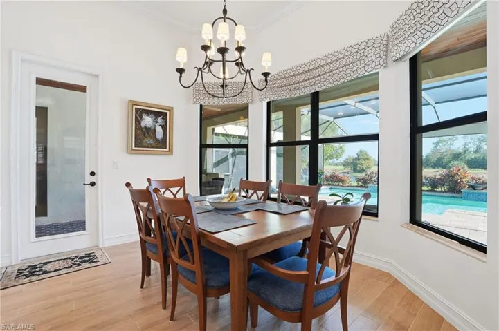 Dining space featuring light wood-style floors, a chandelier, ornamental molding, and a sunroom