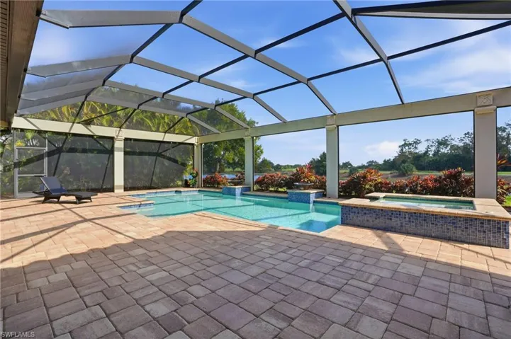 View of pool featuring a lanai, a pool with connected hot tub, a sunroom, and a patio area