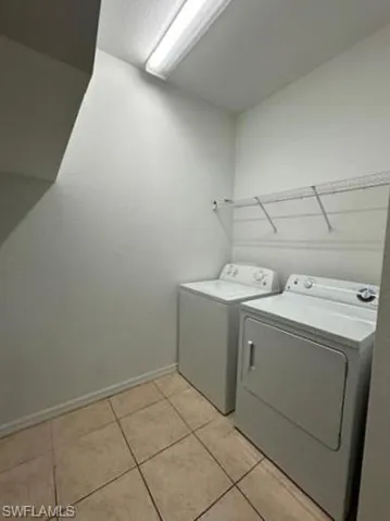 Laundry area featuring washing machine and clothes dryer and light tile patterned flooring
