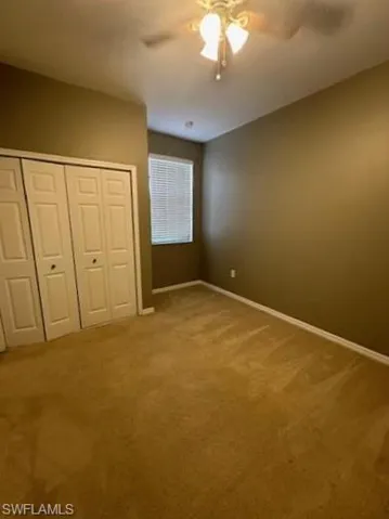 Unfurnished bedroom with light colored carpet, a ceiling fan, and a closet