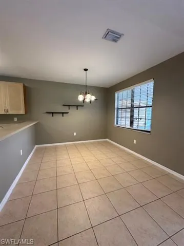 Unfurnished dining area with hanging lights and light tile patterned floors