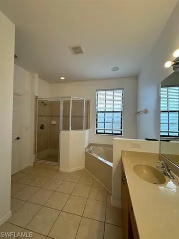 Bathroom featuring a stall shower, vanity, a bath, and light tile patterned floors