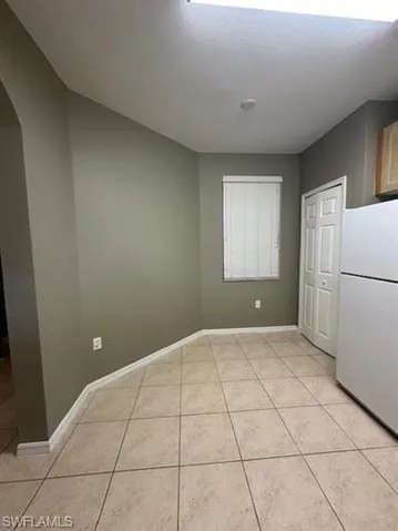 Unfurnished dining area with arched walkways and light tile patterned flooring