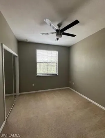 Unfurnished bedroom featuring light colored carpet, a closet, and a ceiling fan