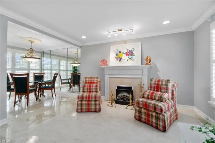 Living room with ornamental molding and a high end fireplace