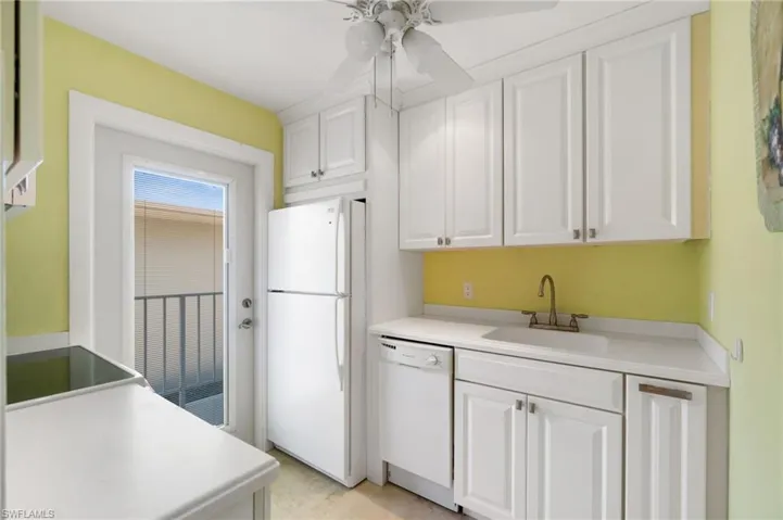 Kitchen with white appliances, white cabinetry, a ceiling fan, and light countertops