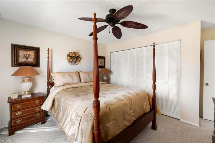 Bedroom with carpet floors, ceiling fan, and a textured ceiling