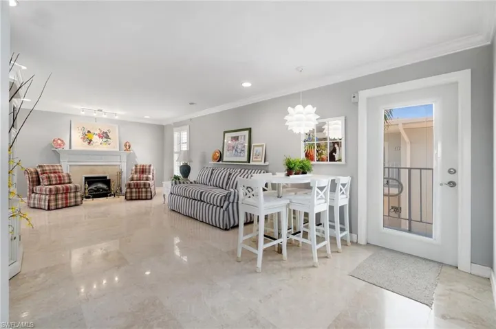Living area featuring ornamental molding, marble tiled floors, a fireplace, and recessed lighting