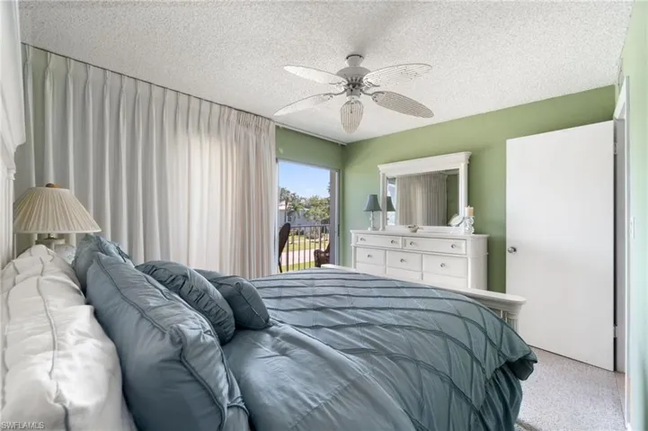 Carpeted bedroom with access to outside, a textured ceiling, and ceiling fan