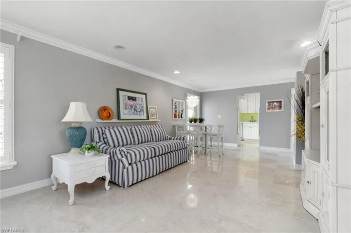Living area featuring ornamental molding, healthy amount of natural light, light marble finish flooring, a chandelier, and recessed lighting