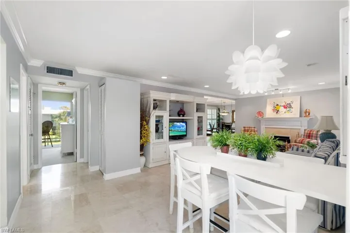 Dining room with crown molding, a chandelier, a fireplace, and recessed lighting