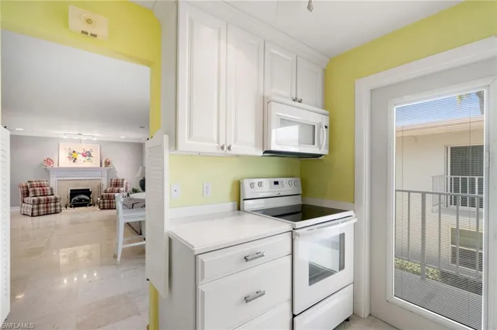 Kitchen with white appliances, white cabinetry, light countertops, and a fireplace