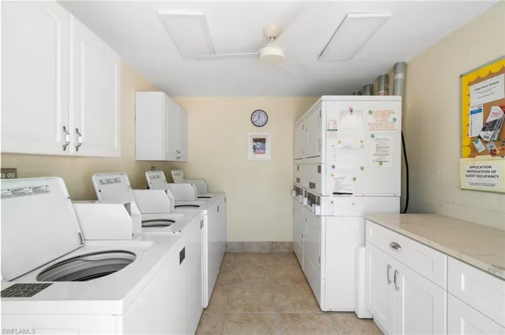 Washroom featuring cabinet space, separate washer and dryer, stacked washing machine and dryer, attic access, and light tile patterned floors