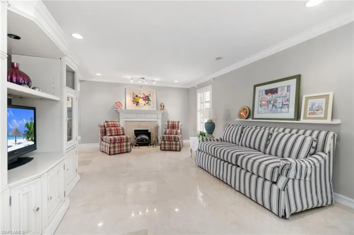 Living room with crown molding, light marble finish floors, recessed lighting, and a fireplace