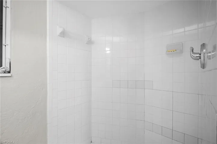 Bathroom view of tiled shower and a textured wall