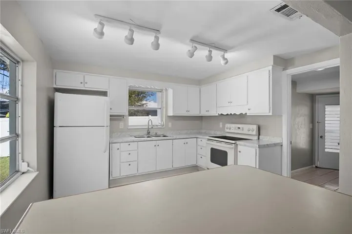 Kitchen featuring white appliances, light countertops, and white cabinetry