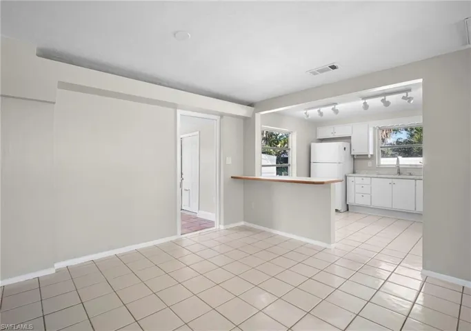 Kitchen featuring white cabinets, light countertops, a peninsula, and plenty of natural light