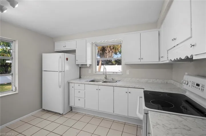 Kitchen with white appliances, white cabinets, light countertops, and light tile patterned floors