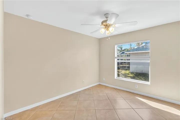 Empty room featuring light tile patterned flooring and ceiling fan