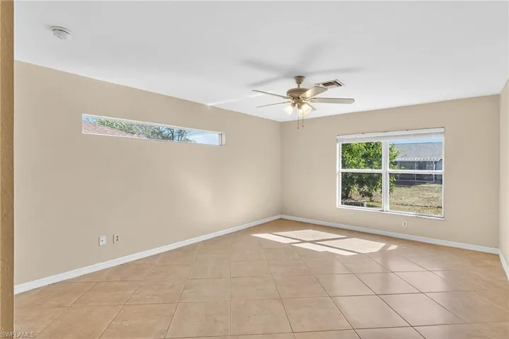 Empty room with a ceiling fan and light tile patterned floors