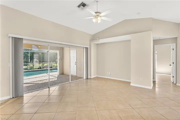 Empty room with ceiling fan, vaulted ceiling, and light tile patterned floors