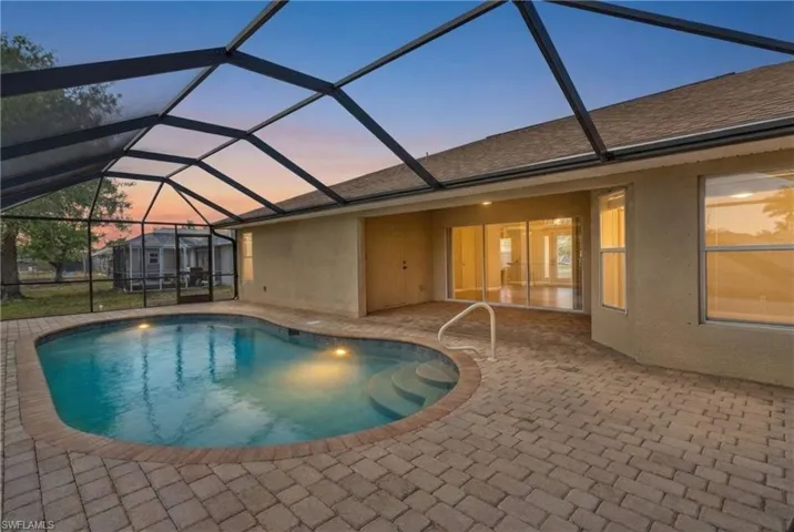 Pool at dusk featuring a sunroom, an outdoor pool, a lanai, and a patio
