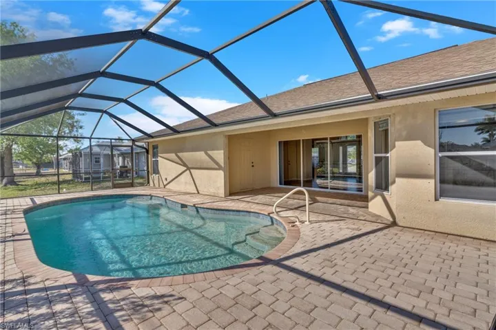 Outdoor pool with a sunroom, a patio area, and glass enclosure