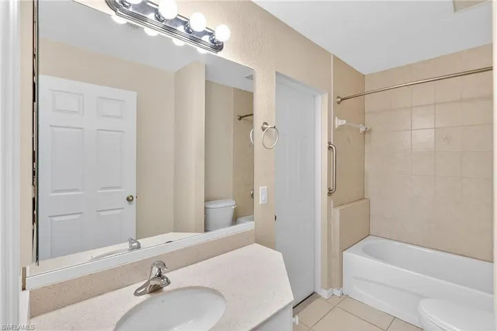 Bathroom featuring vanity, light tile patterned flooring, shower / washtub combination, and a textured wall