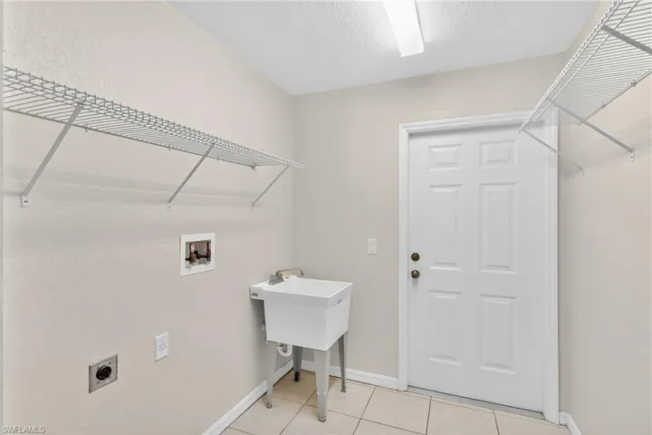 Laundry room with hookup for a washing machine, electric dryer hookup, and light tile patterned flooring