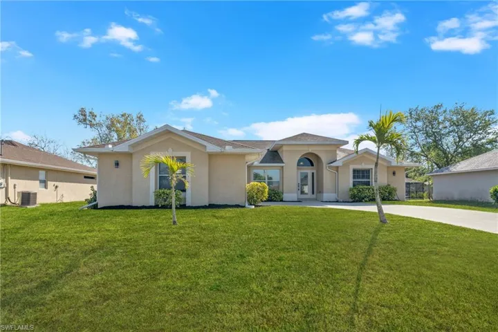 View of front of home featuring stucco siding, a front lawn, and driveway