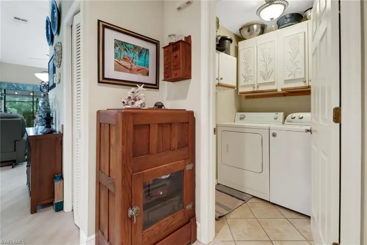 Washroom featuring washing machine and clothes dryer, light tile patterned floors, and cabinets