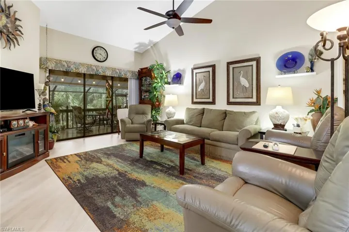 Living room featuring ceiling fan, a fireplace, high vaulted ceiling, and wood-type flooring