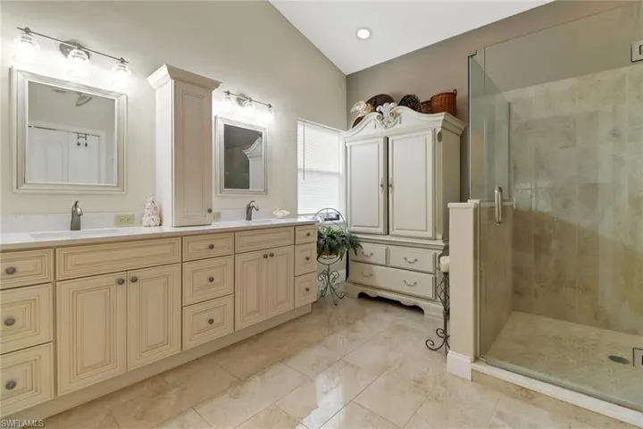 Master Bathroom featuring a shower with door, vanity, and lofted ceiling