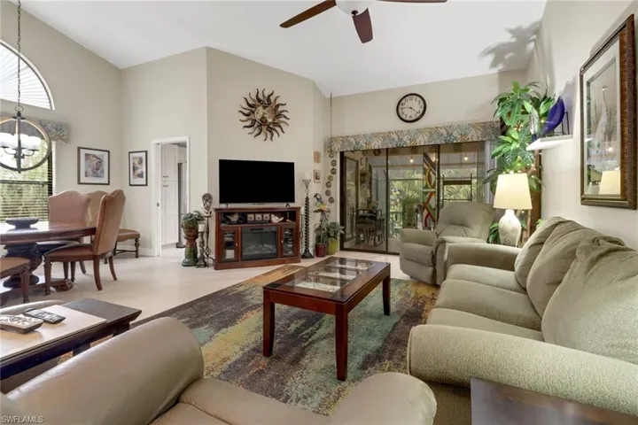 Living room featuring hardwood / wood-style floors, ceiling fan with notable chandelier, and high vaulted ceiling