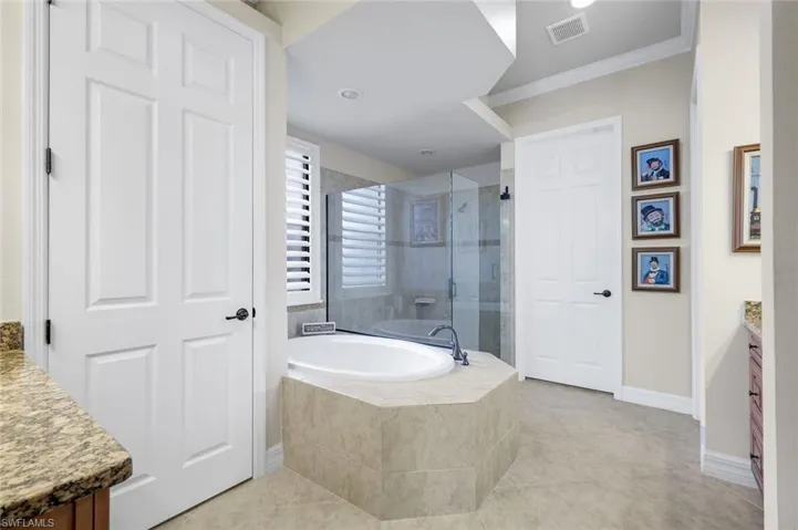 Bathroom with vanity, a garden tub, ornamental molding, a stall shower, and light tile patterned flooring