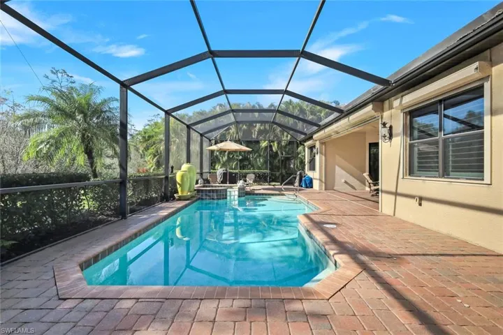 View of swimming pool with a sunroom, a lanai, a pool with connected hot tub, and a patio