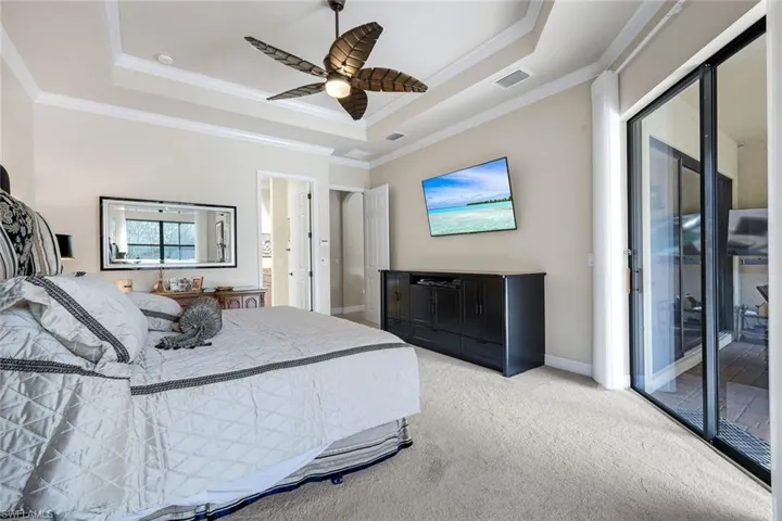 Carpeted bedroom with access to exterior, a raised ceiling, a ceiling fan, and crown molding