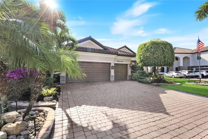 View of front facade featuring decorative driveway, stucco siding, an attached garage, and a tile roof