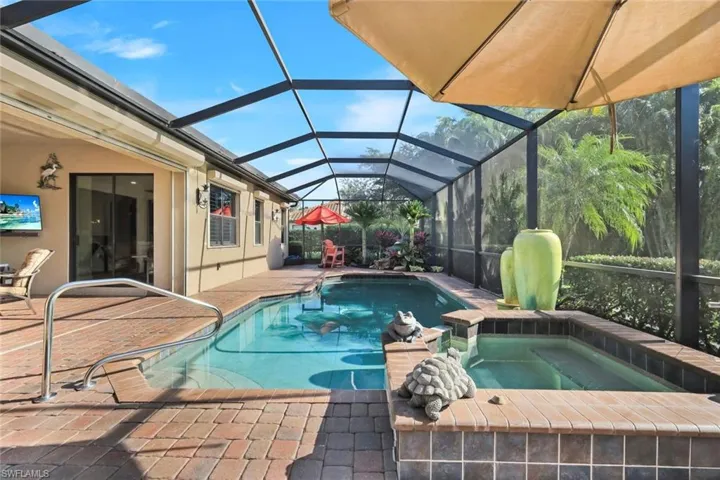View of pool with a sunroom, a patio, glass enclosure, and a pool with connected hot tub