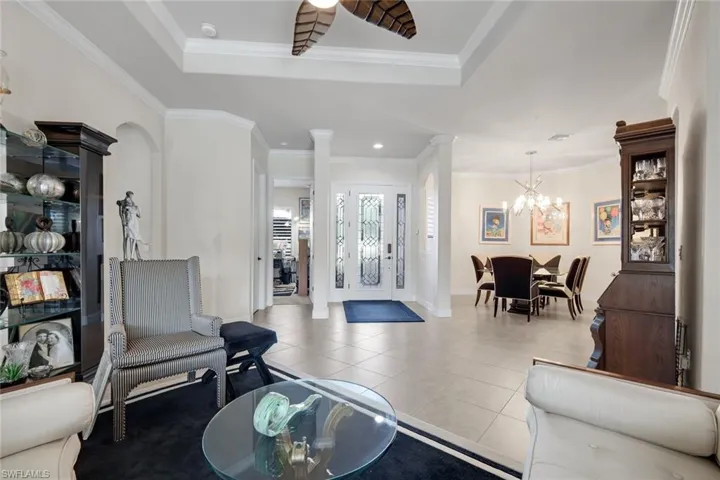 Foyer featuring light tile patterned flooring, ornamental molding, ornate columns, a chandelier, and recessed lighting