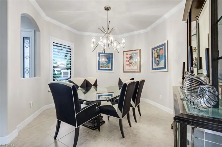 Dining room featuring arched walkways, a chandelier, crown molding, and light tile patterned floors