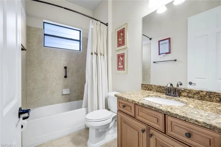 Bathroom featuring vanity, shower / bath combo, and light tile patterned flooring