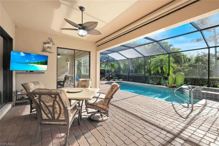 View of pool with a patio area, a sunroom, glass enclosure, a pool with connected hot tub, and outdoor dining space