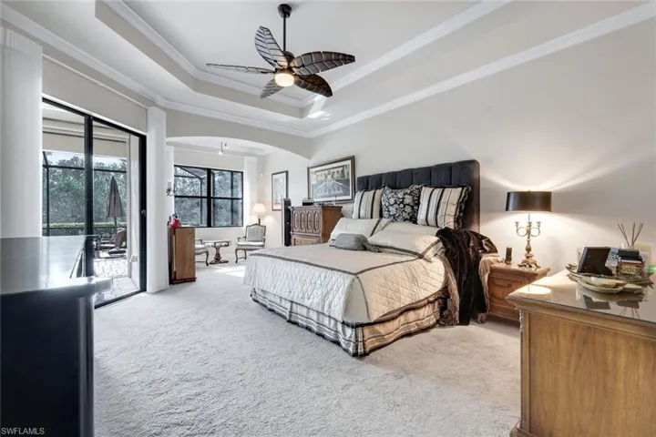 Carpeted bedroom with ornamental molding, a tray ceiling, access to exterior, and ceiling fan