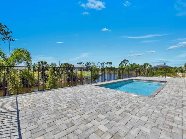 View of swimming pool featuring fence, a water view, a patio area, and a fenced in pool