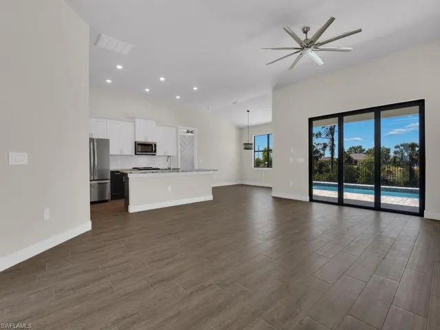 Unfurnished living room with baseboards, dark wood-type flooring, and ceiling fan