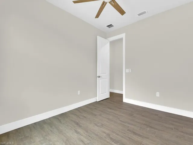 Spare room featuring baseboards, ceiling fan, visible vents, and wood finished floors