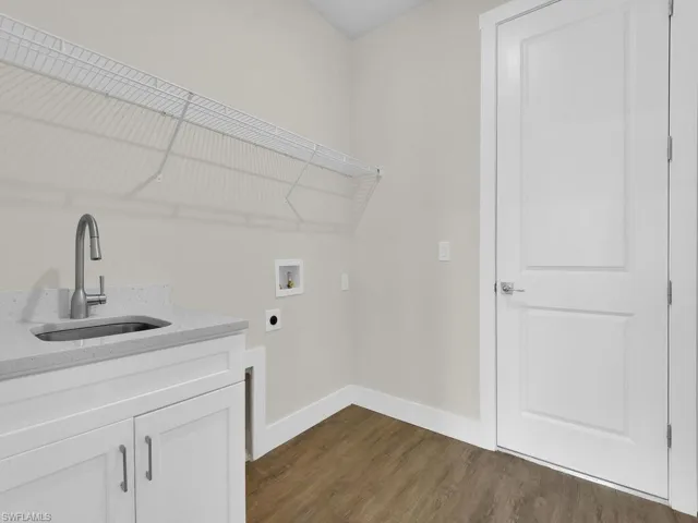 Clothes washing area featuring a sink, hookup for a washing machine, baseboards, dark wood-type flooring, and hookup for an electric dryer